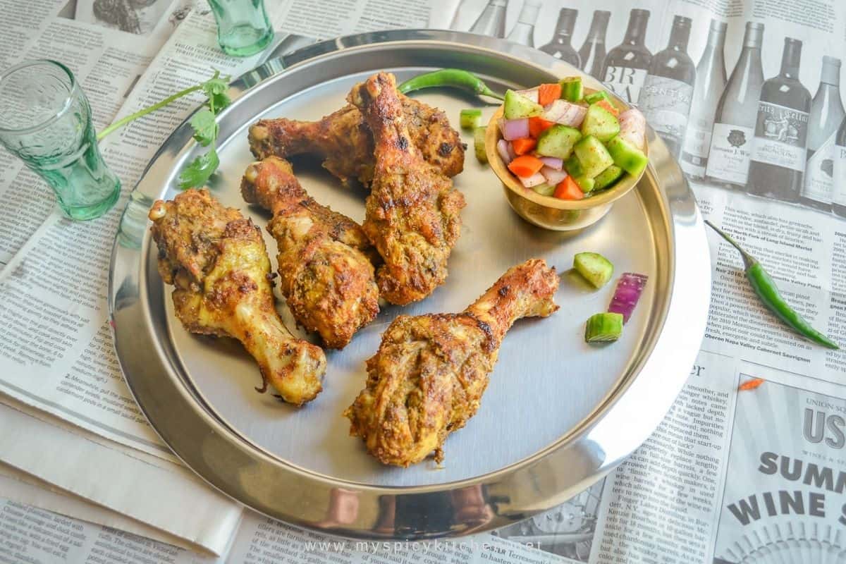 A round platter of spicy grilled chicken with some cucumber carrot relish on the side.