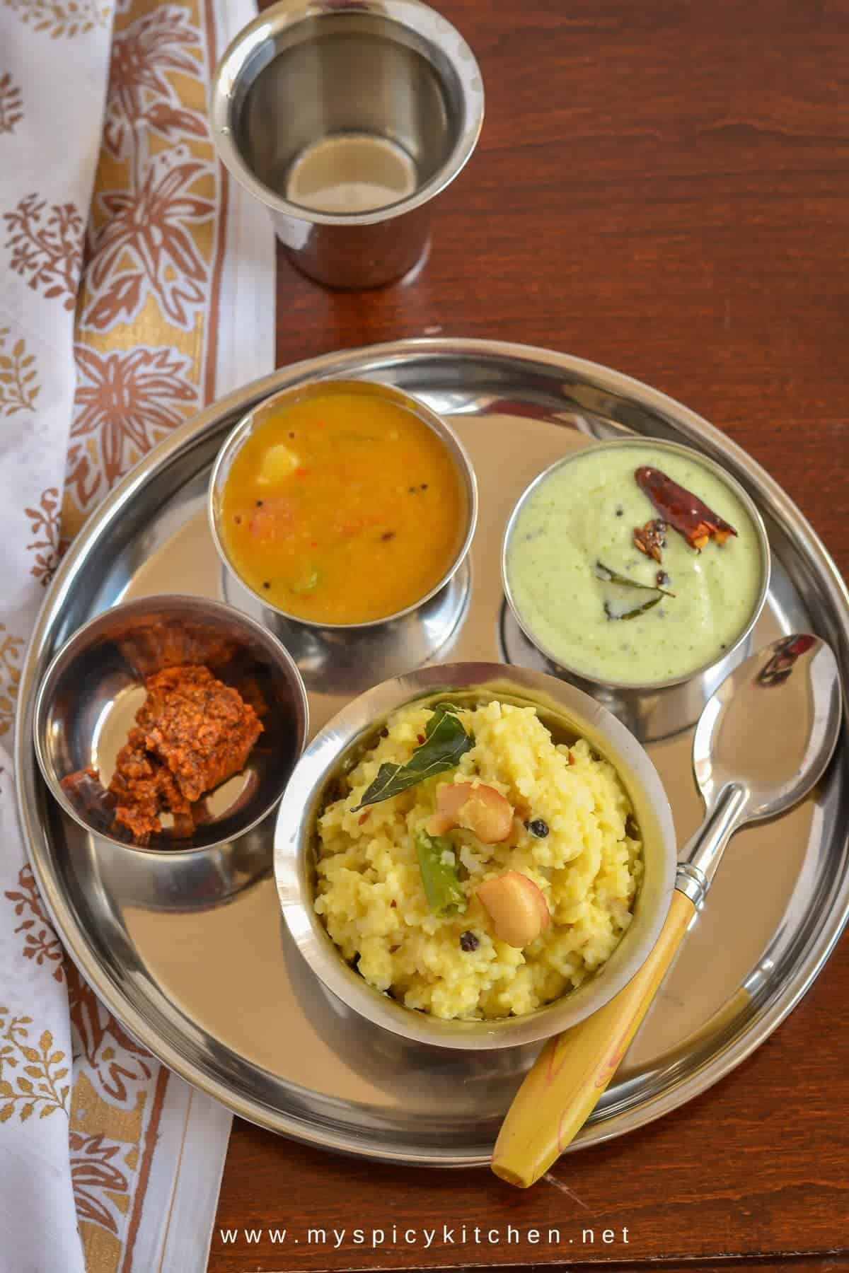 A platter of ven pongal, sambar, chutney and pickle.