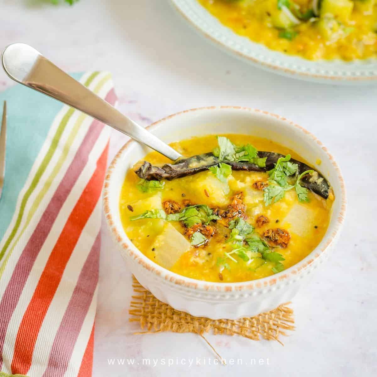 A bowl of zucchini dal with a spoon