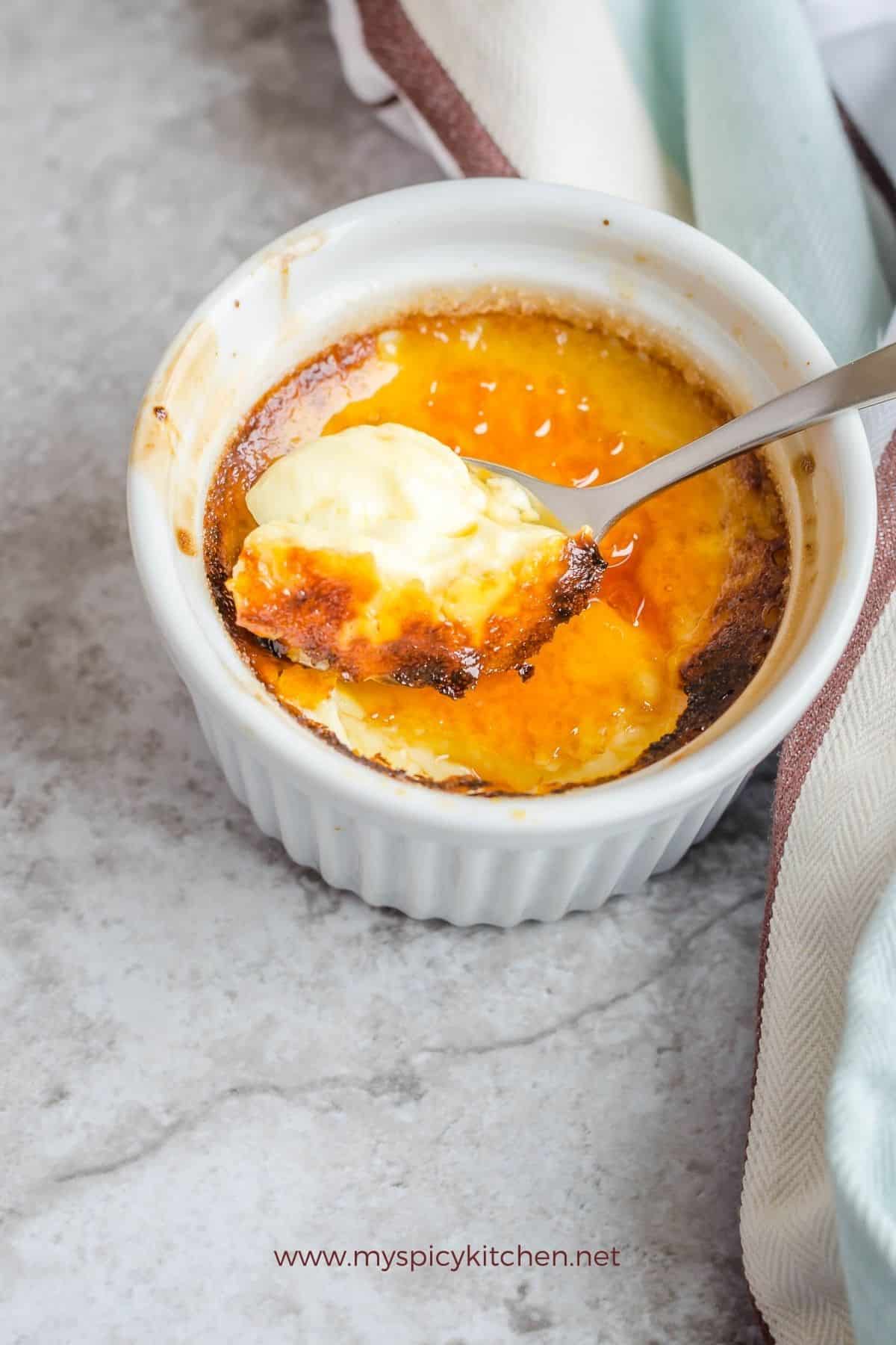 Spoon on orange cinnamon custard on a bowl of custard.