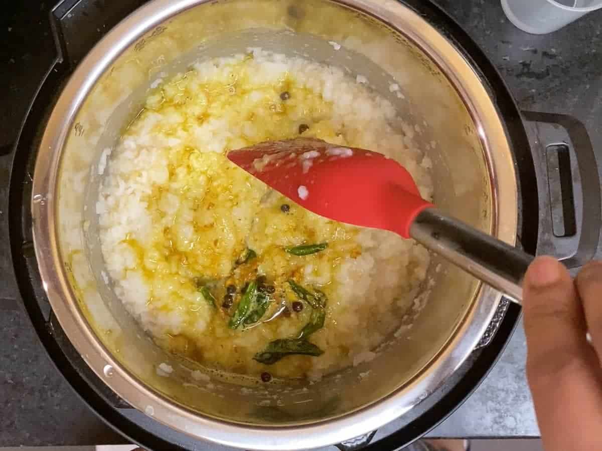 SBS preparation of pongal - putting it all together by adding tempering to cooked rice dal porridge.
