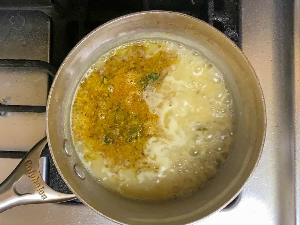 Tadka over boiling pappu khut in a saucepan.